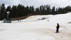 Få små skid- och snowboardåkare hade vågat sig ut i duggregnet på måndagen i Borgå. En snötäckt skidbacke med några enstaka personer som åker ner.