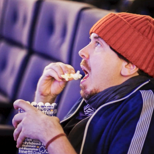 Kuvassa Viikon Tuukka eli Tuukka Pasanen istuu elokuvateatterin penkillä katsomassa sivulle kohti valkokangasta ja on juuri laittamassa popcornia suuhunsa