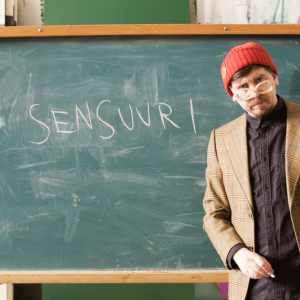 Kuvassa Viikon Tuukka eli toimittaja Tuukka Pasanen seisoo liitutaulun edessä 50-luvun opettajamaiset lasit päässään, taululla lukee sensuuri.