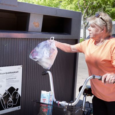 kuvassa nainen kierrättää muovia