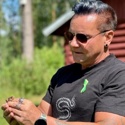 En man i solglasögon håller i en groda.