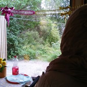 Asylsökande kvinna vid fönstret i sitt hem vid Raasepori Resort som ska stängas.
