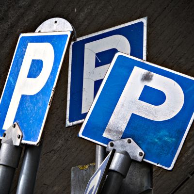 Pysäköinnin sallivia liikennemerkkejä varaston edessä.