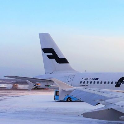 Ett Finnairflyg står på marken vid Helsingfors-Vanda flygplats. Ett annat flygplan syns i förgrunden. Det är snö på marken.