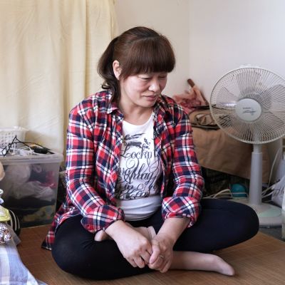 Kiinalainen ompelija Guo Yuqin istuu lattialla. Hashima, Japani.