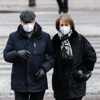 Människor i munskydd går i Helsingfors centrum i februari 2021.