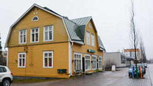 Samaria Groups loppishus är för tillfället till salu. Ett stort gult trähus invid en gata. På en skylt står det Samaria.