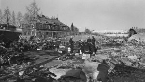 Lapuan patruunatehtaan räjähdyksen raunioita 13.4.1976. Pelastusmiehet istuvat patruunalaatikoilla onnettomuuspaikalla.