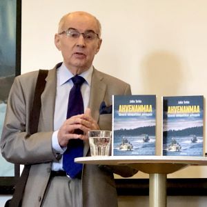 Jukka Tarkka presenterar sin nya Ålands-bok i Helsingfors Jukka Tarkka med två exemplar av sin nya Ålandsbok.