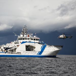 Räddningshelikopter landar på en patrullbåt ute till havs. 