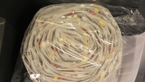 Så här ser en rulle med färdigt paketerade piller ut. I en rulle finns mediciner för två veckor. Flera små plastpåsar som sitter samman med varandra har rullats ihop. Inne i plastpåsarna syns olika sorts piller. Plastpåserullen är innanför ett skilt plasthölje. Det är frågan om dosdispenseringspåsar.