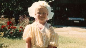 Roh Petas i gulvit klänning, ljusröda och vita smycken och hatt med breda brätten. Troligen 1990. Roh Petas i gulvit klänning, ljusröda örhängen och vit hatt med breda brätten. I början av 1990-talet