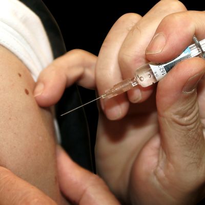 En vaccineringsnål sticks in i armen.