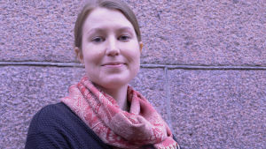 Jennifer Holmberg ger råd och tips för Lovisa- och Lappträskbor. En ung kvinna i svart tröja och röd halsduk tittar in i kameran. Hon står utomhus framför en stenvägg.