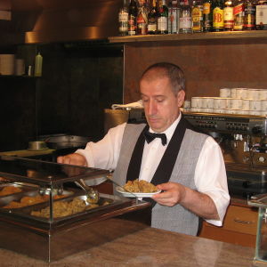 Tarjoilija annostelee tapaksia lautaselle baaritiskin takana espanjalaisravintolassa.