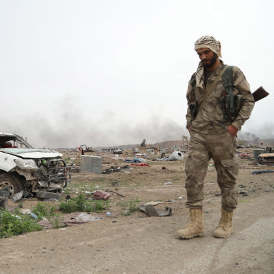 Kurdisk soldat vandrar förbi förstörd materiel i västra Syrien som använts av islamiska staten IS.