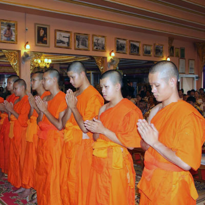 Pojkarna sitter i orange buddhistmunkskåpor i templet. 
