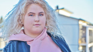 Matilda Rehnstrand förundrar sig över hus som står tomma i Majberget. En ung kvinna står utanför ett våningshus. Hon tittar in i kameran utan att le.