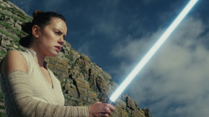 Rey (Daisy Ridley) är inte ovan att hålla i ett lasersvärd. Rey (Daisy Ridley) tittar förundrat på sitt lasersvärd.