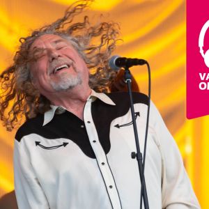 Robert Plant står bakom en mikrofonställning och slänger blundande huvudet bakåt så håret flaxar.