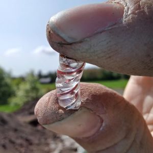 En bit venetianskt glas från 1600-talet som hittades vid en utgrävning visas mellan tumme och pekfinger