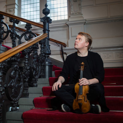 viulisti Pekka Kuusisto istuu viulu kädessä portaikossa