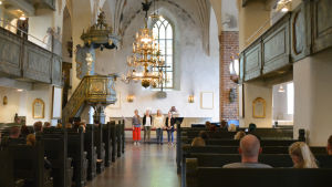Kvartetten Frida. Längst fram syns altaret i Borgå domkyrka och fyra sjungande kvinnor. I bänkraderna sitter en hel del människor, främst unga par.