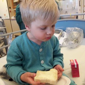 Sairaala on Oivalle tuttu, mutta pelkoa herättävä paikka. Lapsi sairaalan vuoteen reunalla. Syö leipää