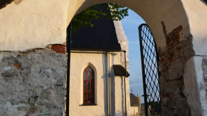 Just nu besöker många helst sådana utflyktsmål där man kan vara utomhus och hålla avstånd till andra. En kvällspromenad runt Borgå domkyrka uppfyller kriterierna. Genom kyrkporten syns en del av Borgå domkyrka i kvällssolen.