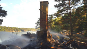 Endast skorstenen står kvar. En skorsten står kvar efter bastu som brunnit till grunden.
