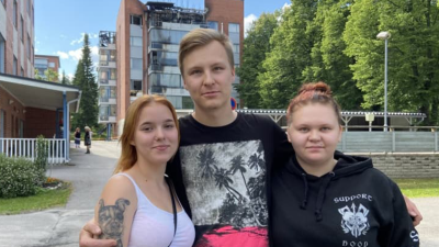 Eerika Pasanen, Samu Silventoinen och Sari Veijalainen står framför ett flervåningshus som brunnit