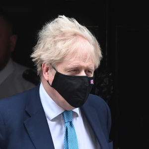 Boris Johnson går ut från Downing Street med munskydd på.