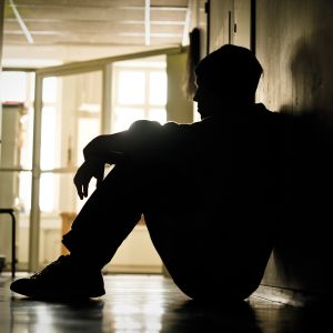ungdom sitter ensam i en korridor
