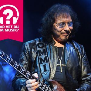 Tony Iommi blundar, ler och spelar elgitarr.