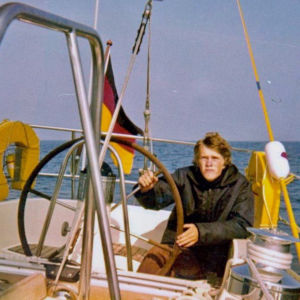 Anders Skogman har vuxit upp i Jakobstad och har seglat i flera årtionden. På heltid har han seglat i 16 år. Den här bilden är tagen 1974 någonstans på Östersjön. En man sitter i aktern på en segelbåt och håller i ratten.