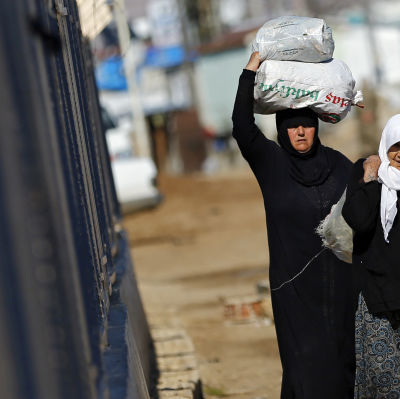Syriska kvinnor bär på mat vid den Turkiska gränsen.