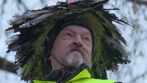 Matti Uutela katselee kaukaisuuteen valtava sulkahattu päässään.