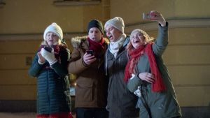 Månssonin perhe laulaa joululauluja ulkona lumisateessa.