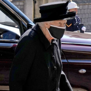 En sörjande änka i pandemitider. Drottningen vid prins Philips begravning den 17 april 2021. Drottning Elizabeth II i svarta sorgekläder och svart munskydd på väg mot St George's Chapel i Windsor.