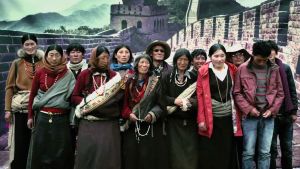 Tiibetiläisperhe poseeraa valokuvaajalle Kiinan muurin kuvan edessä