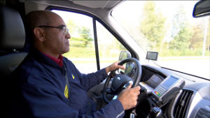 Miragha tränar sina nya språk dagligen genom att prata med kunderna. Taxichaufför sitter vid ratten i sin bil.