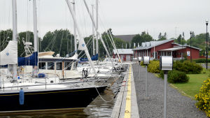 I samma område som mässan planeras finns Ingås småbåtshamn. Flera båtar står förtöjda vid en brygga i en hamn. I bakgrunden syns ett rött hus.