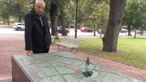 I närheten av domkyrkan kan man hitta den här minnesstenen som visar hur stadsplanen i Åbo såg ut före branden. En man vid en staty som föreställer gamla åbo