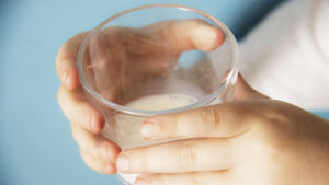 lasillinen maitoa lapsen käsissä ja tekstigrafiikkana väite maidon terveellisyydestä