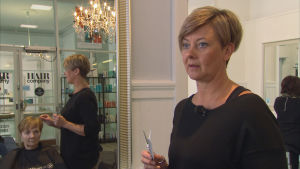 Anna Wiik hinner inte handleda praktikanter i den mån hon skulle vilja. Kvinnlig frisör framför spegel i frisörsalong.