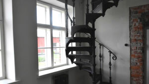 Spiraltrappan har väntat i ett lager på rätt hus. Nu finns den i ett renoverat hus på bostadsmässan. En gammal svartmålad spiraltrappa går upp i en renoverat hus.