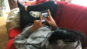 Poika lojuu sohvalla ja selaa Instagramia