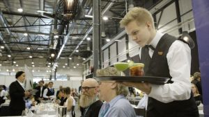 Johan Lindström serverar gäster på Mästare-tävlingen i yrkeskunskap. Johan Lindström serverar mat på Mästare-tävlingen.