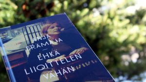Anja Erämajan teos edessä ja takana metsää ja pensaita