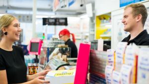 Fler privatpersoner skickar paket över R-kioskens disk under poststrejken. Ung kvinna ger ett Ärräpaket över disken till R-kioskens personal